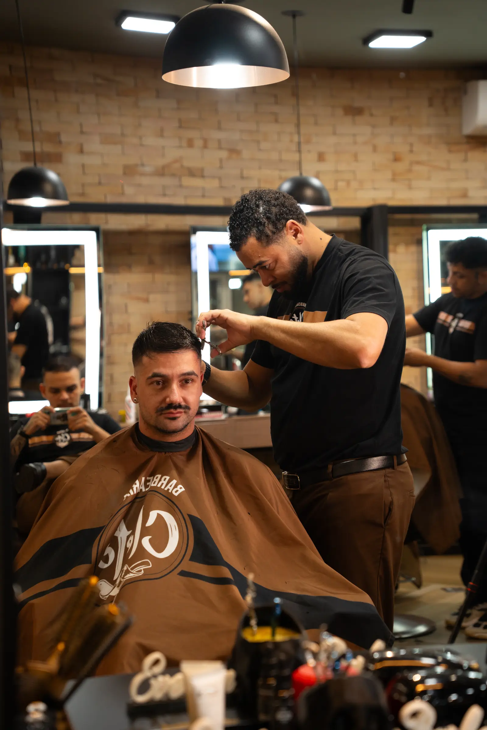 Barbeiro finalizando o corte de um cliente no salão da Cleto